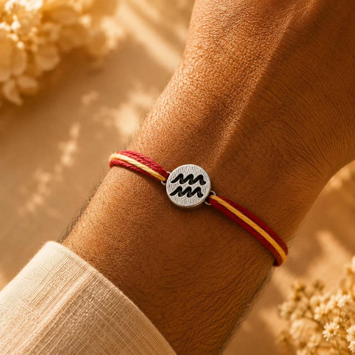 925 silver Aquarius zodiac rakhi on a red and gold braided thread