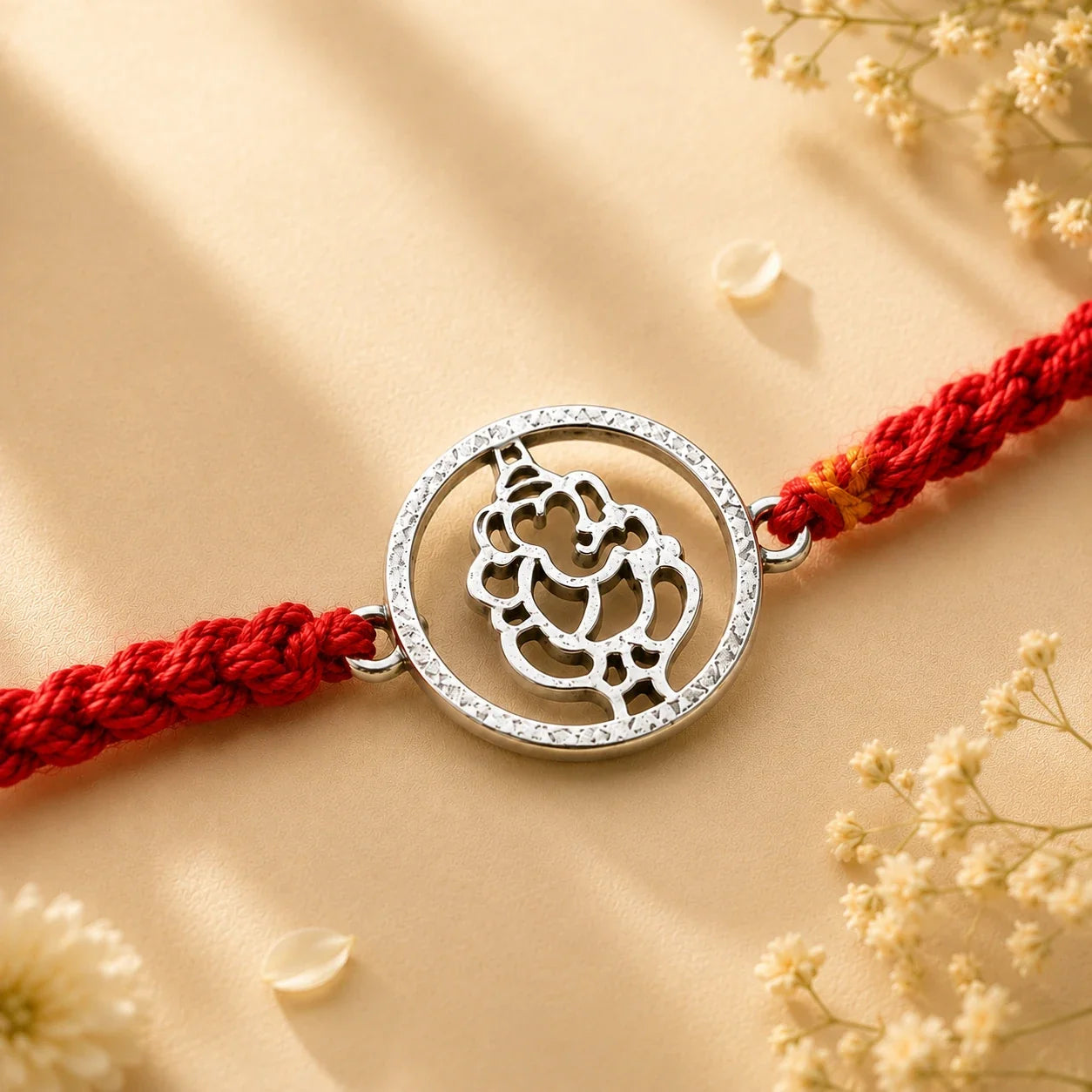 925 silver Round Ganesha rakhi with a Ganesha motif in a circular frame on a red braided thread