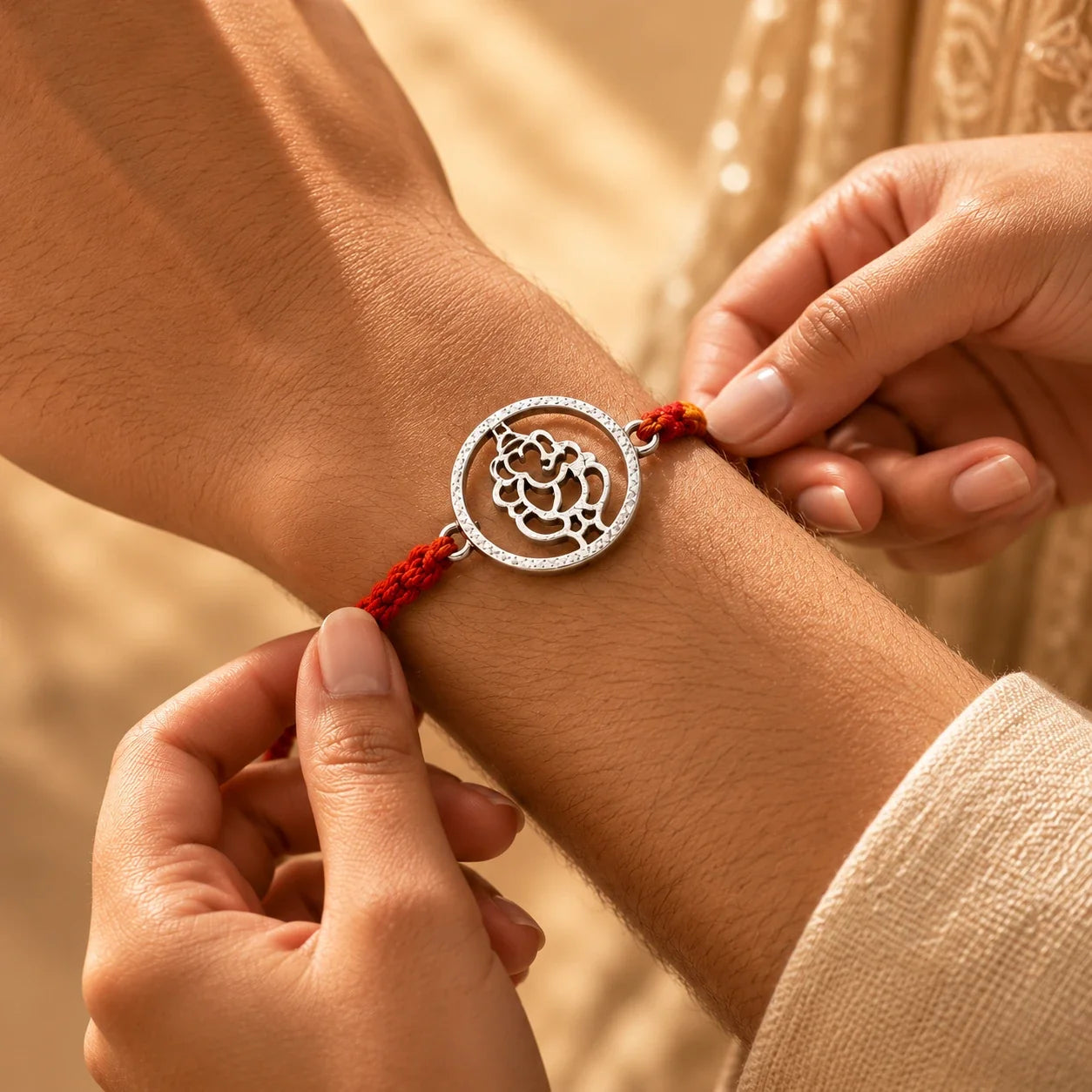 925 silver Round Ganesha rakhi with a Ganesha motif in a circular frame on a red braided thread