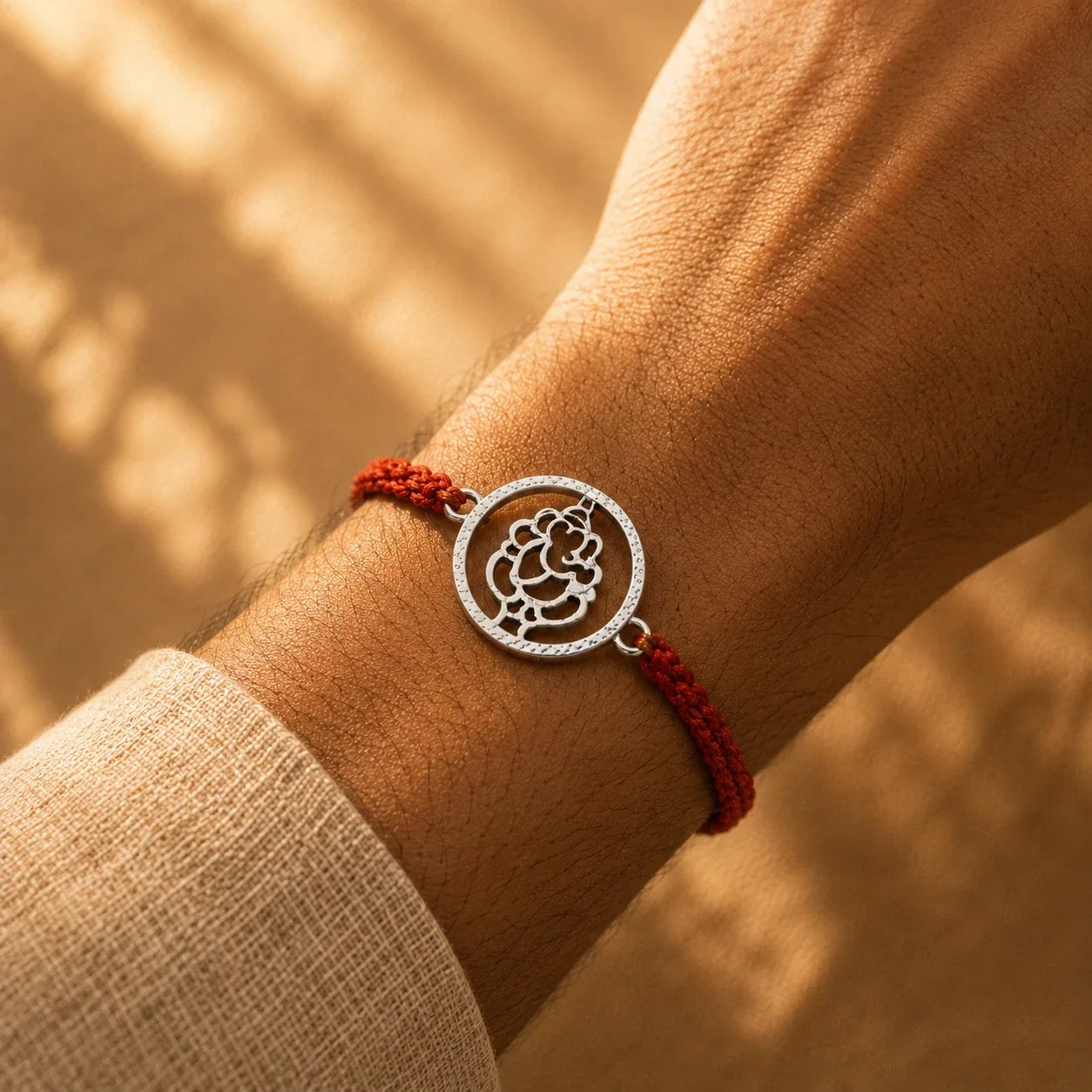 925 silver Round Ganesha rakhi with a Ganesha motif in a circular frame on a red braided thread
