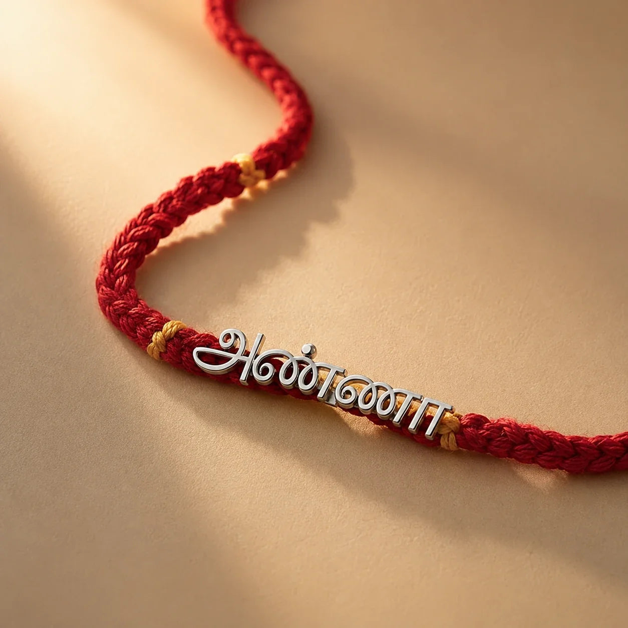925 silver Tamil Anna rakhi with அண்ணா engraved in Tamil script on a red braided thread