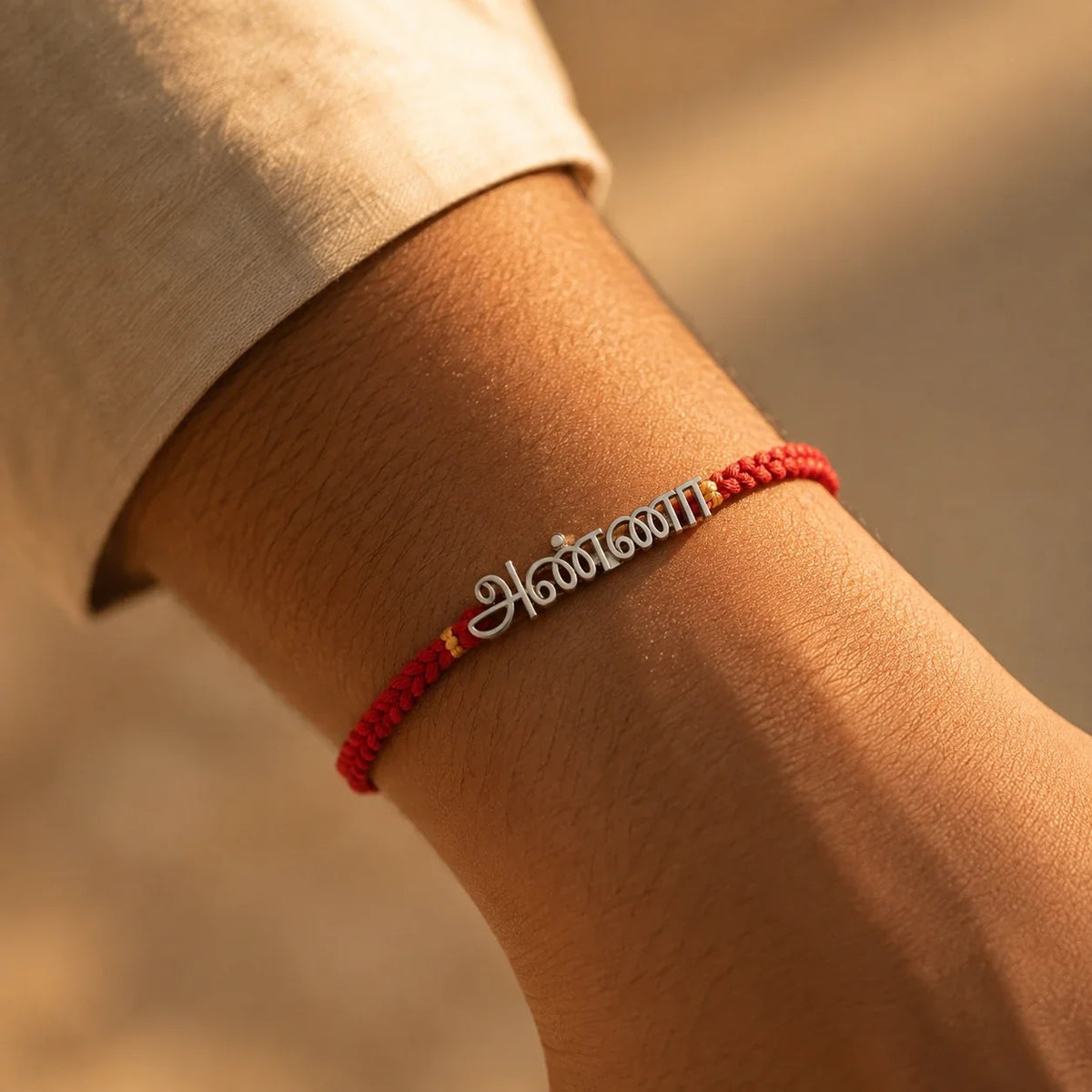 925 silver Tamil Anna rakhi with அண்ணா engraved in Tamil script on a red braided thread